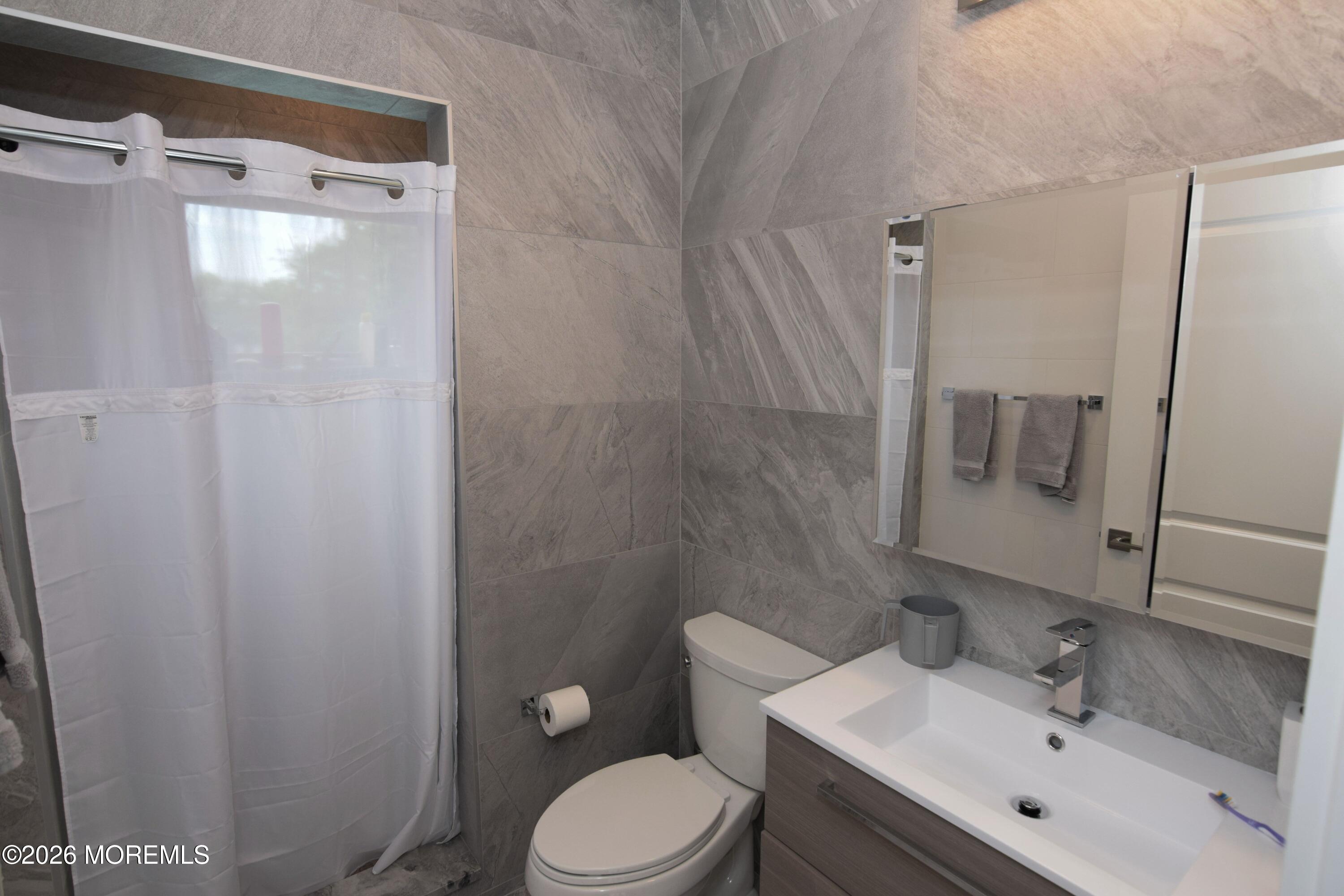 229 Lockwood Avenue, Unit WINTER Long Branch, NJ 07740 - Photo 14 of 19 a bathroom with a sink mirror vanity and toilet