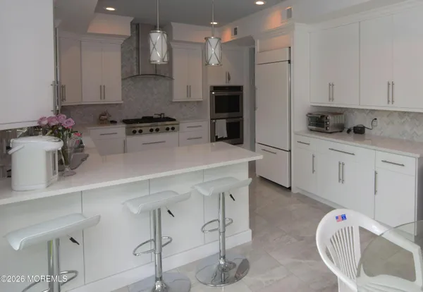 a kitchen with stainless steel appliances a sink a stove a refrigerator and cabinets
