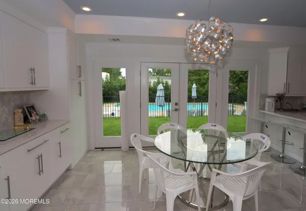 a view of a dining room with furniture a chandelier and large windows