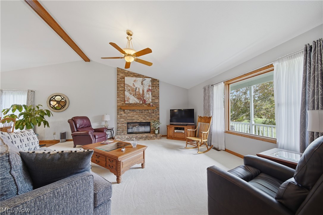 118 Manning Road Mogadore, OH 44260 - Photo 2 of 45 Spacious living area featuring a vaulted ceiling with exposed wood beams, a brick fireplace, and a ceiling fan