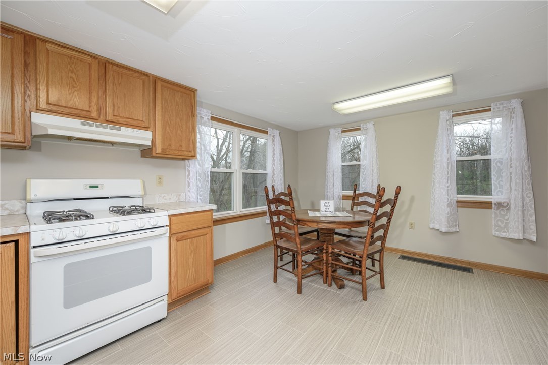 1069 West Nimisila Road New Franklin, OH 44216 - Photo 7 of 26 The kitchen features light wood cabinetry, a white range with an overhead vent, and light-colored countertops