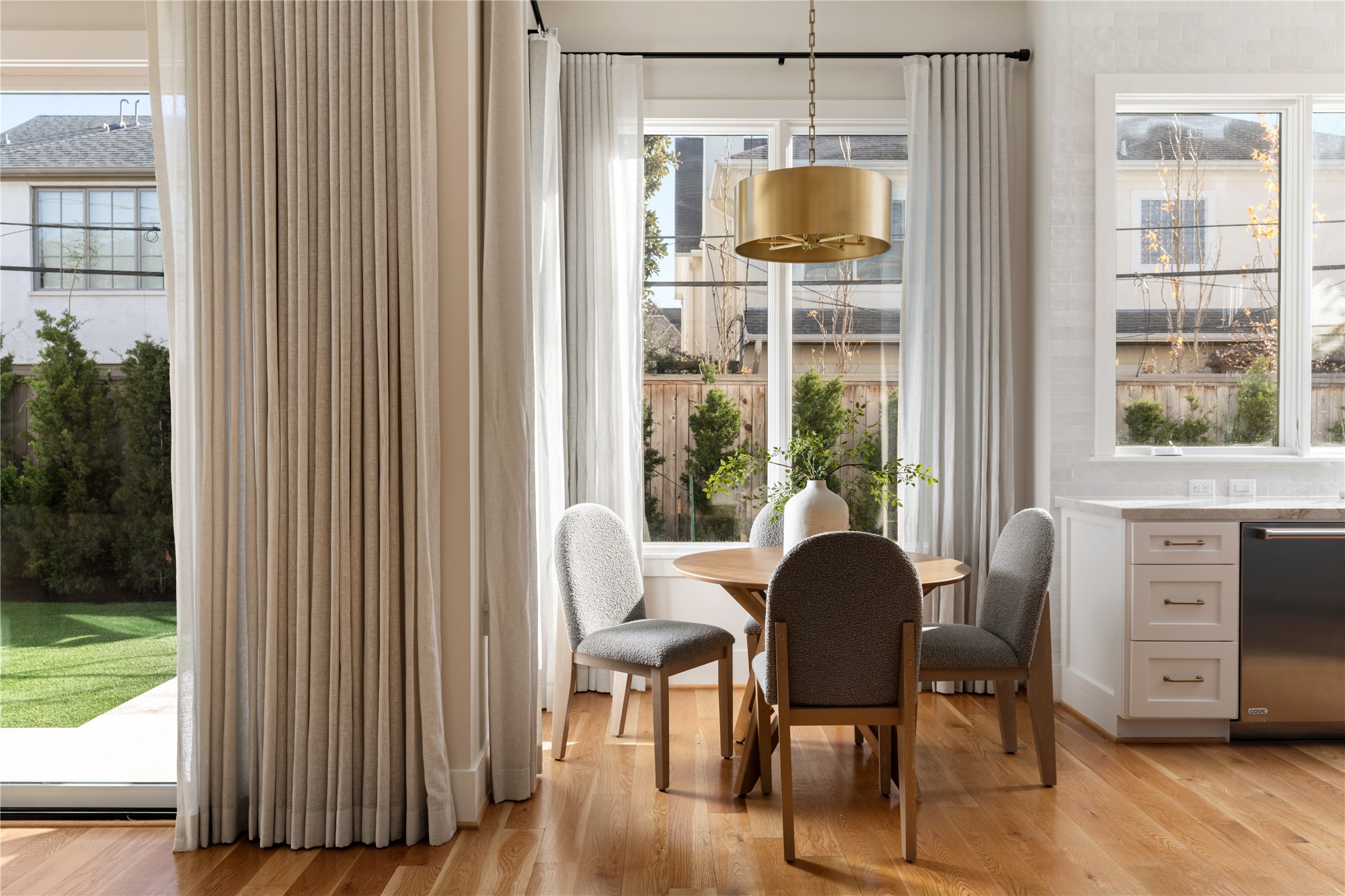 2715 Robinhood Street Houston, TX 77005 - Photo 22 of 48 A sunlit breakfast nook sits beneath a statement pendant, framed by floor-to-ceiling drapery and garden-facing windows that create a warm, inviting space for casual dining.