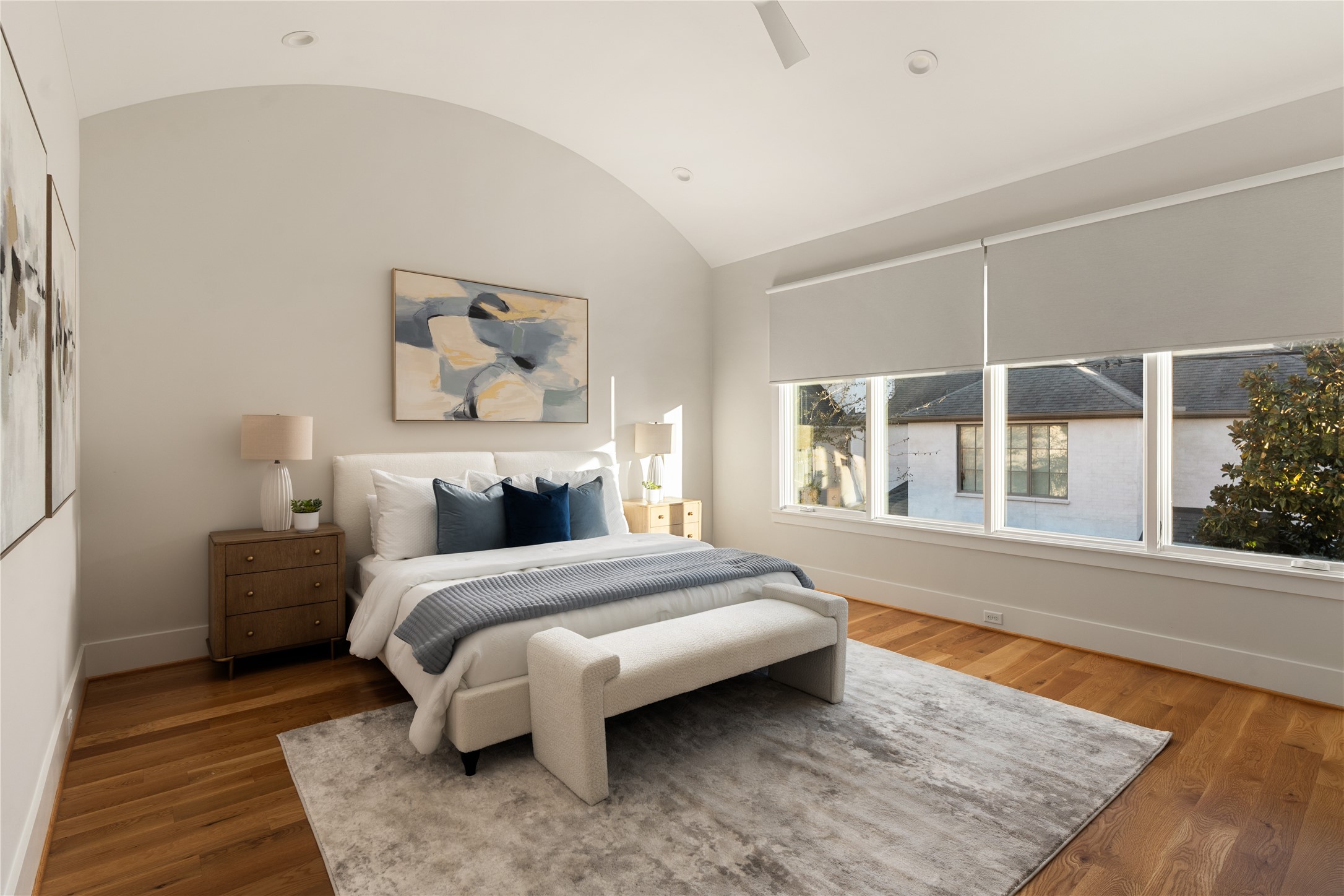 2715 Robinhood Street Houston, TX 77005 - Photo 26 of 48 This serene primary bedroom offers vaulted ceilings, wide-plank hardwood floors, and expansive windows that fill the space with natural light, creating a calm and inviting retreat.