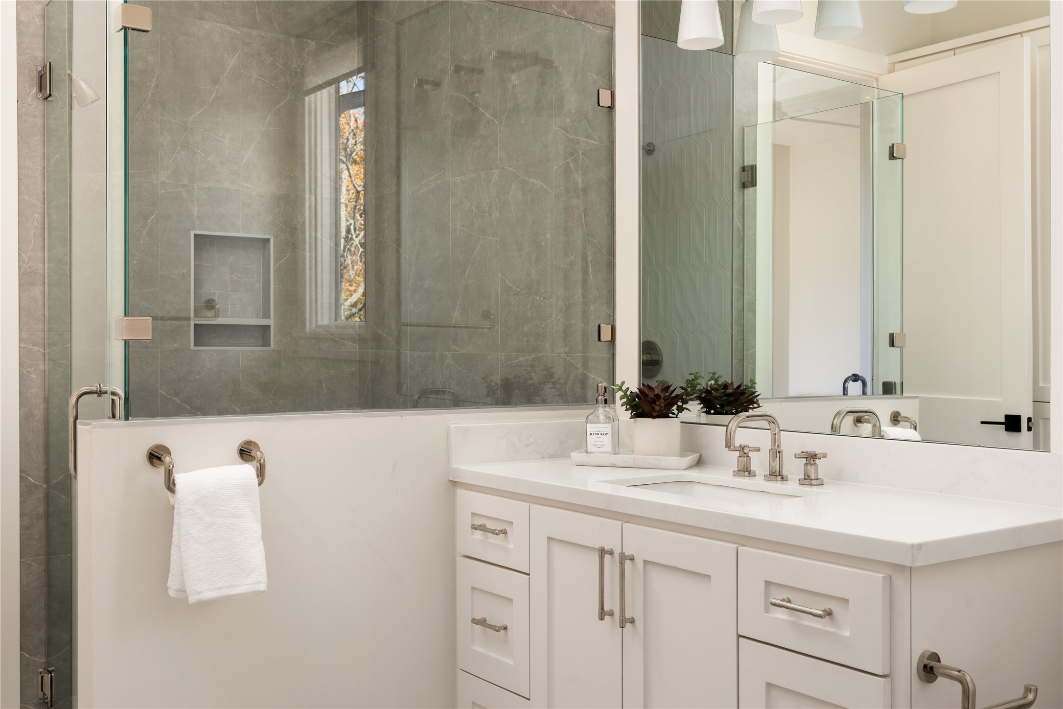 2715 Robinhood Street Houston, TX 77005 - Photo 34 of 48 This refined bath showcases a sleek glass-enclosed shower paired with a crisp white vanity, polished fixtures, and layered lighting that create a clean, spa-inspired retreat.