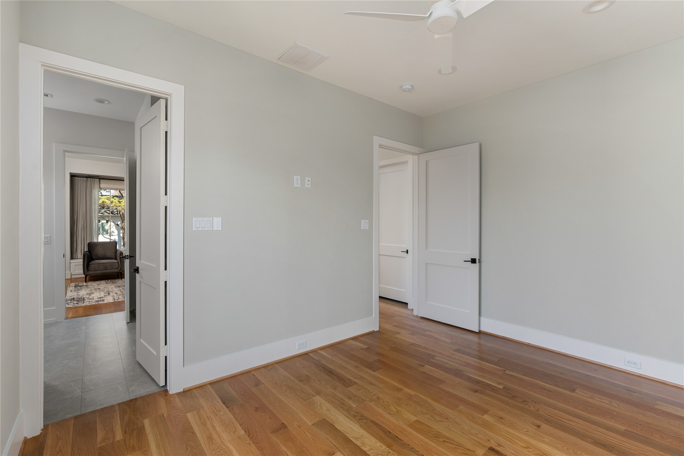 2715 Robinhood Street Houston, TX 77005 - Photo 35 of 48 This light-filled secondary bedroom features warm hardwood floors, soft neutral walls, and a ceiling fan, offering a flexible and inviting space for guests, a home office, or a cozy retreat.