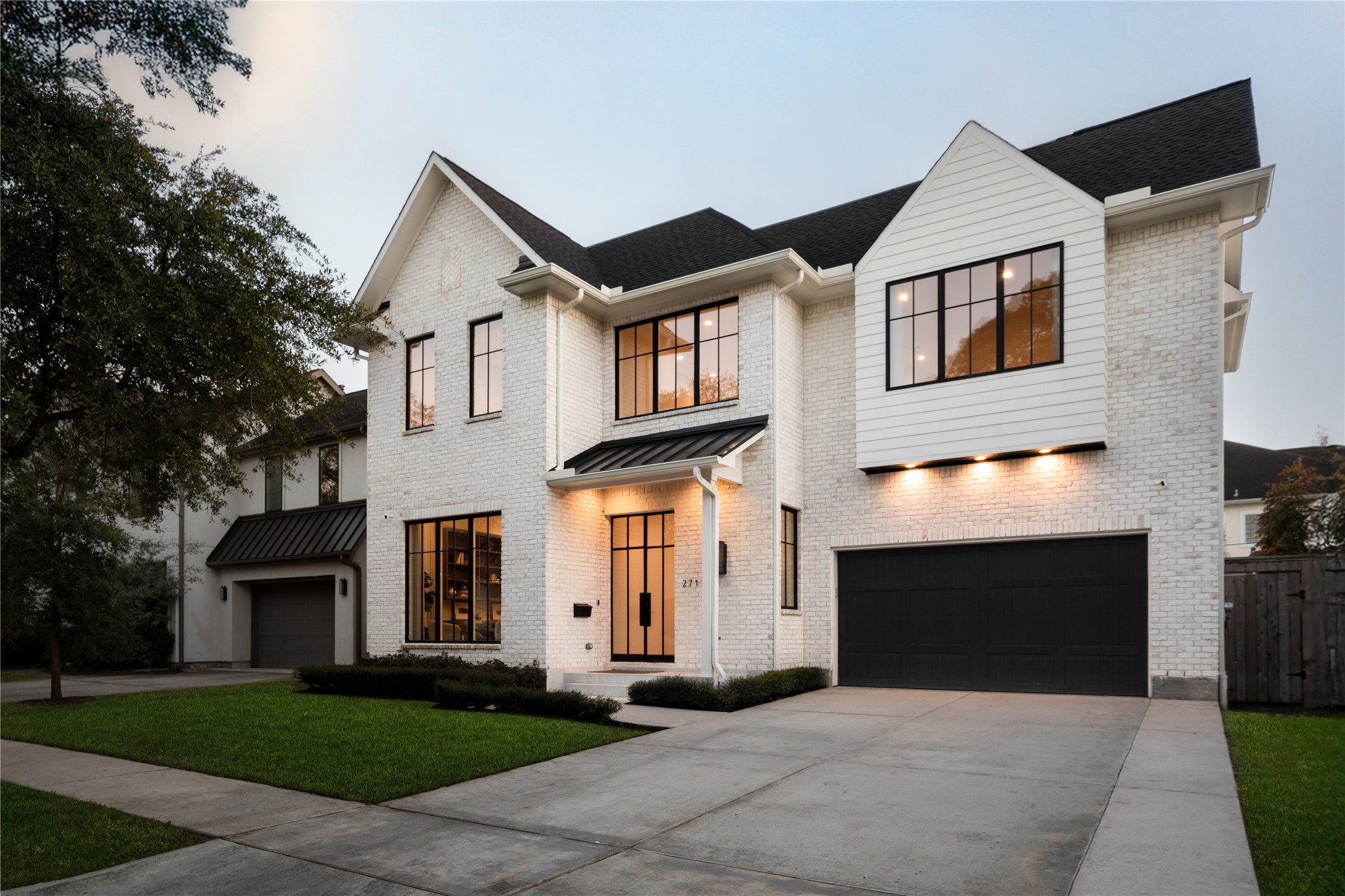 2715 Robinhood Street Houston, TX 77005 - Photo 48 of 48 Striking modern architecture showcases a crisp white brick exterior, bold black-framed windows, and a welcoming glass-front entry, all anchored by a spacious driveway and manicured lawn for polished curb appeal.