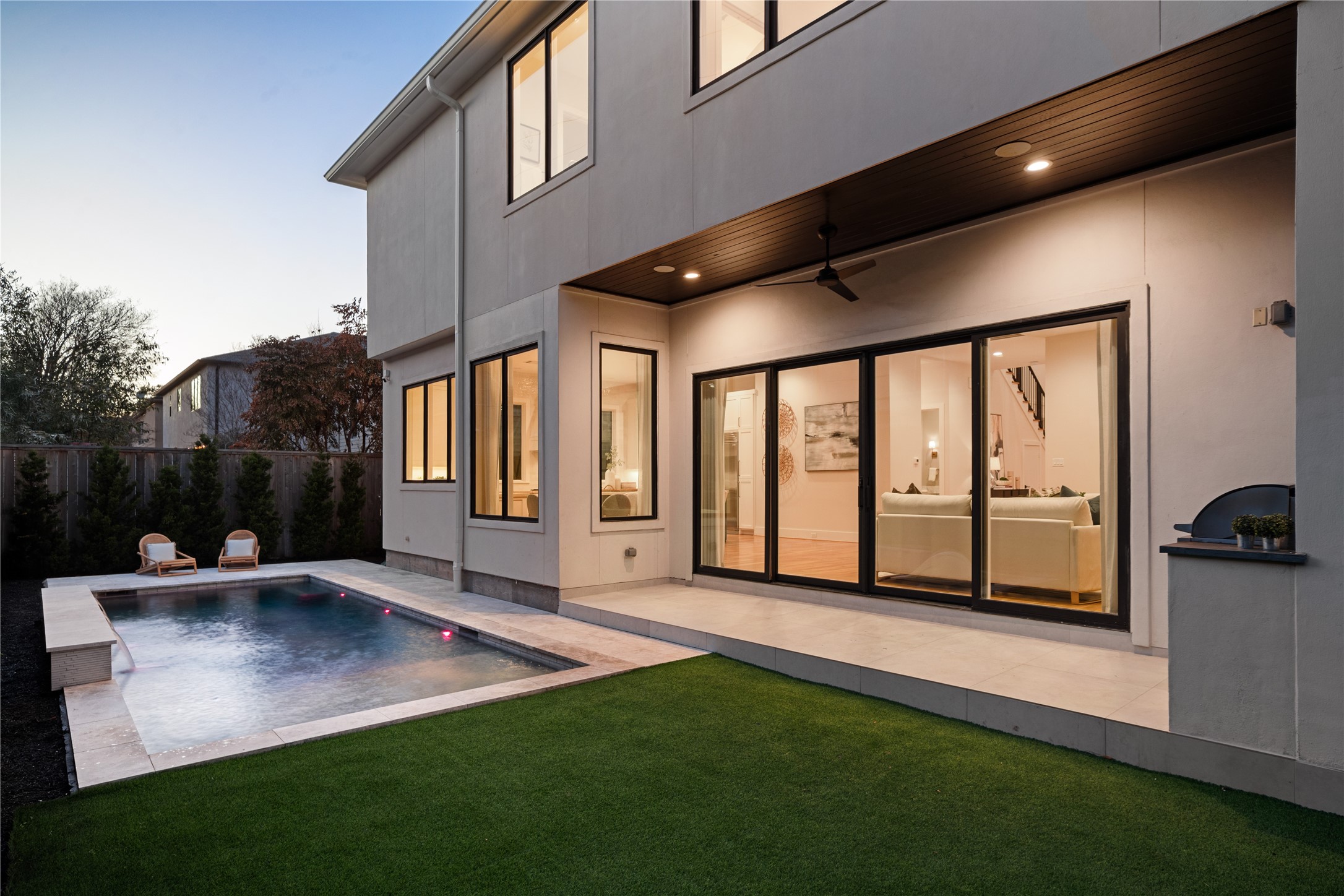 2715 Robinhood Street Houston, TX 77005 - Photo 5 of 48 This private backyard retreat features a sleek, resort-style pool framed by clean-lined hardscaping and lush green lawn, creating an ideal setting for relaxation and entertaining. Expansive sliding glass doors and a covered patio with modern ceiling fan extend the living space outdoors, seamlessly connecting interior comfort with outdoor enjoyment.