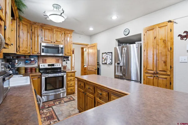a kitchen with stainless steel appliances granite countertop a refrigerator a stove and a sink