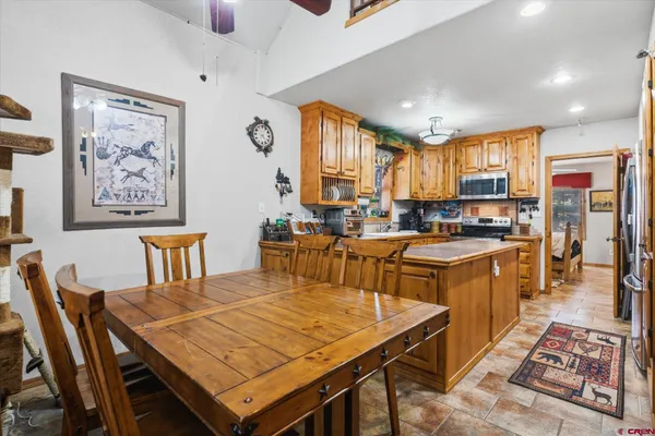 a kitchen with stainless steel appliances granite countertop a stove a refrigerator a kitchen island a table and chairs