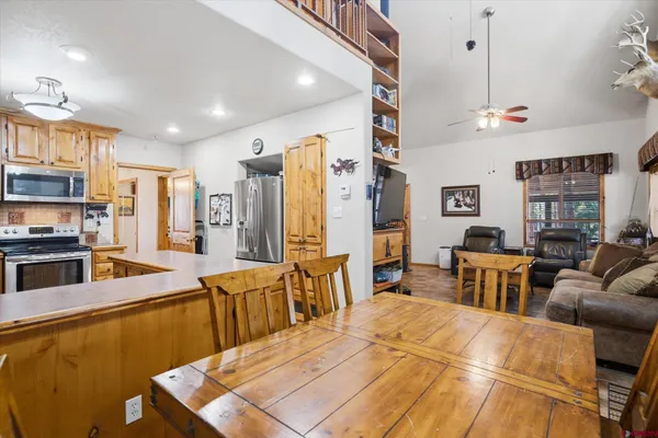 a large kitchen with stainless steel appliances a stove a sink dishwasher a dining table and chairs with wooden floor
