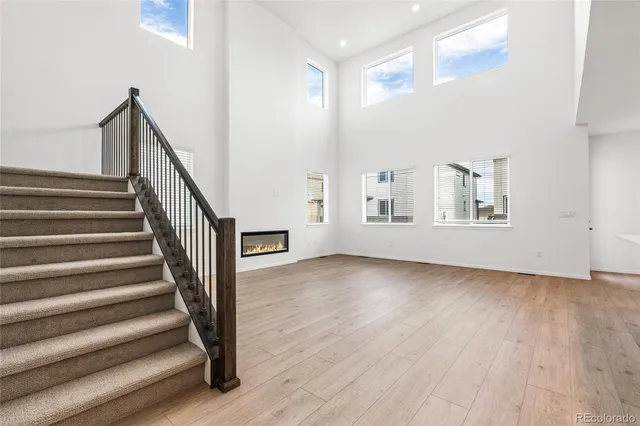 a view of an empty room with wooden floor and fan