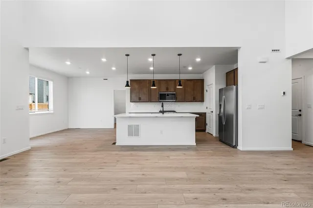 a view of kitchen with stainless steel appliances kitchen island a sink dishwasher a refrigerator and a fireplace with wooden floor
