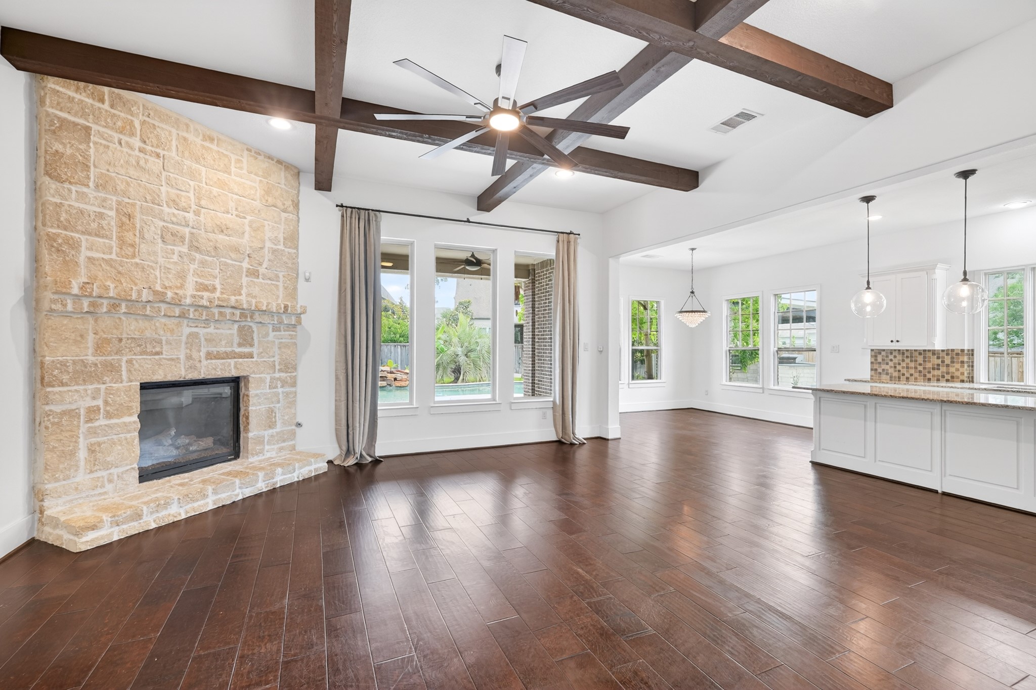 27 Hedgedale Way Spring, TX 77389 - Photo 12 of 49 an empty room with wooden floor a fireplace a ceiling fan and kitchen view