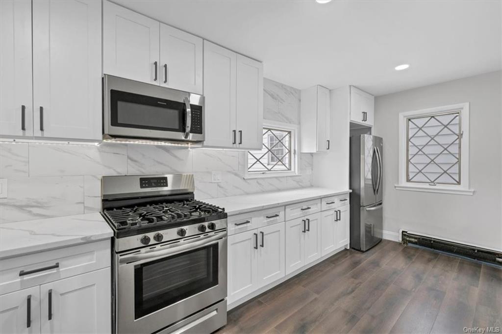 a kitchen with stainless steel appliances white cabinets a stove a sink and a microwave