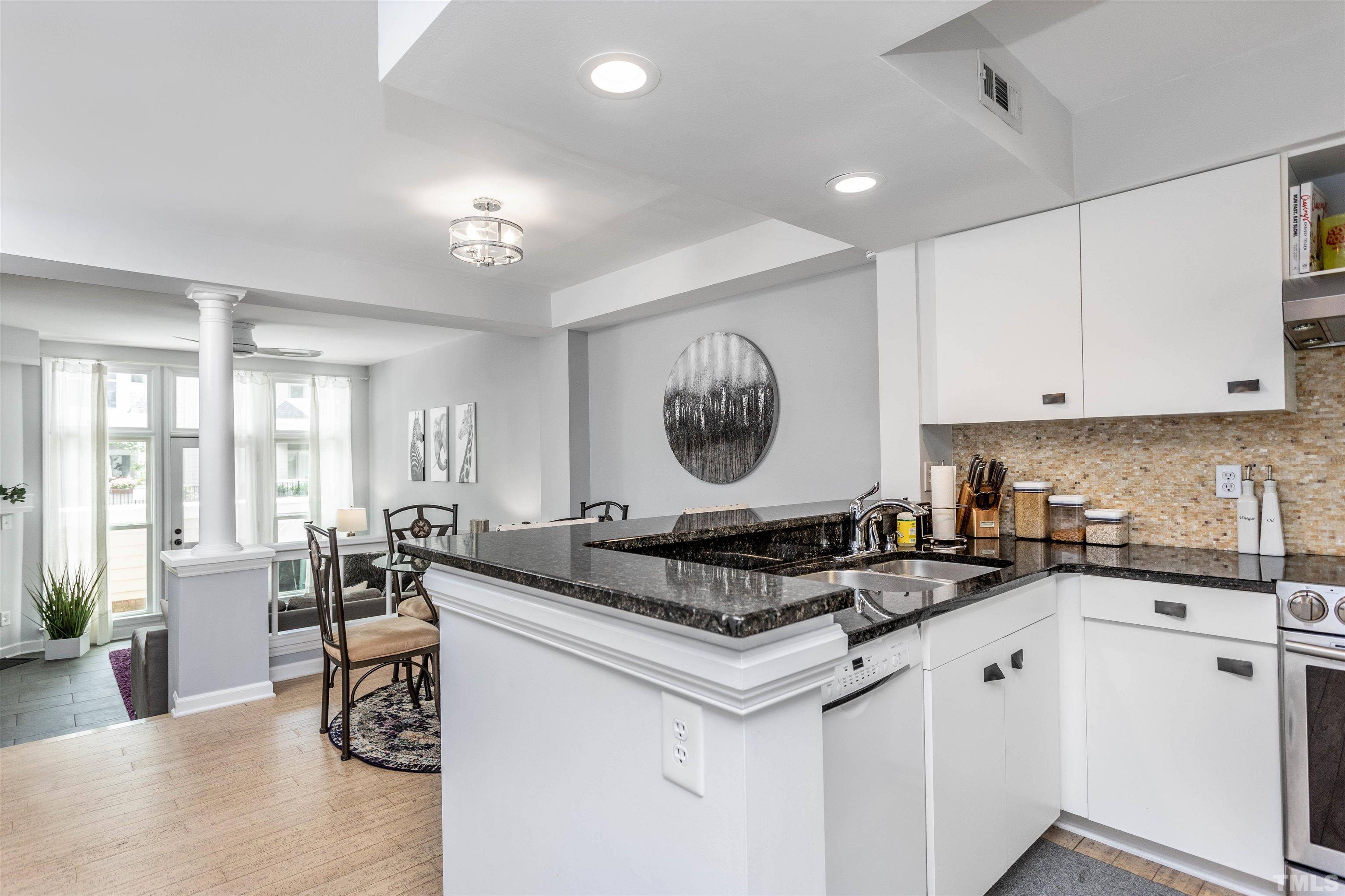 a kitchen with granite countertop a stove a sink a dining table and chairs
