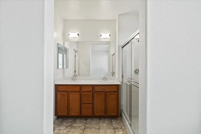 a bathroom with a double vanity sink mirror and shower