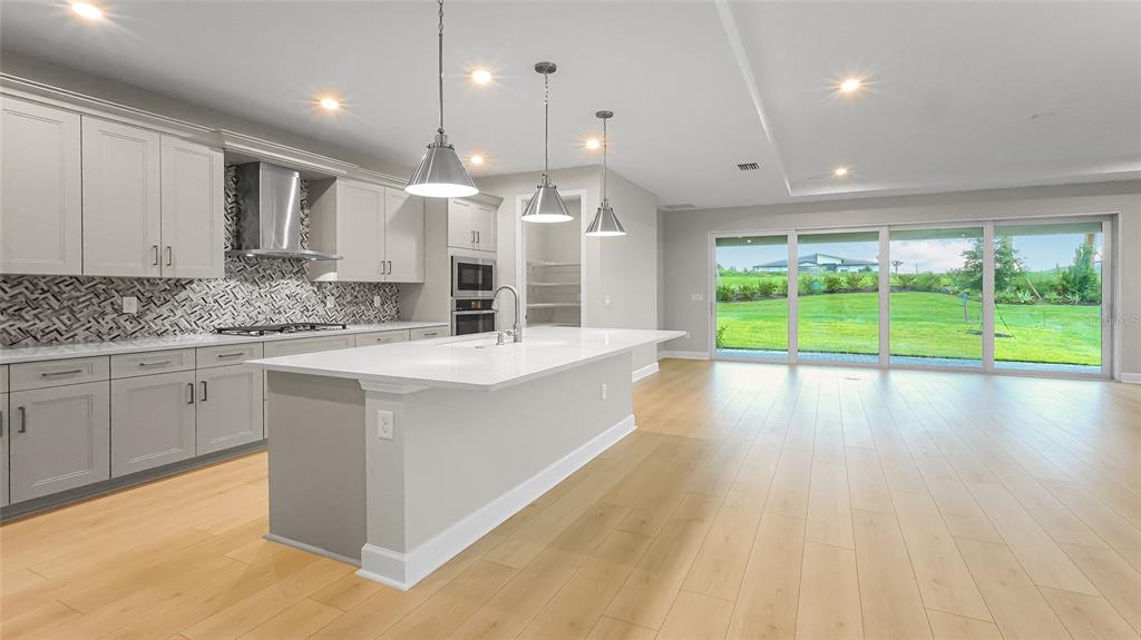 1620 Bellagio Loop Tavares, FL 32778 - Photo 14 of 81 a large kitchen with stainless steel appliances a large counter top a stove a chimney a sink and a large window