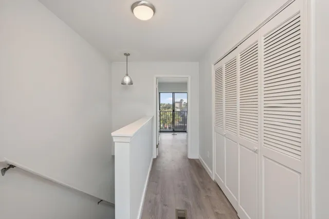 a view of a hallway with wooden floor and cabinets