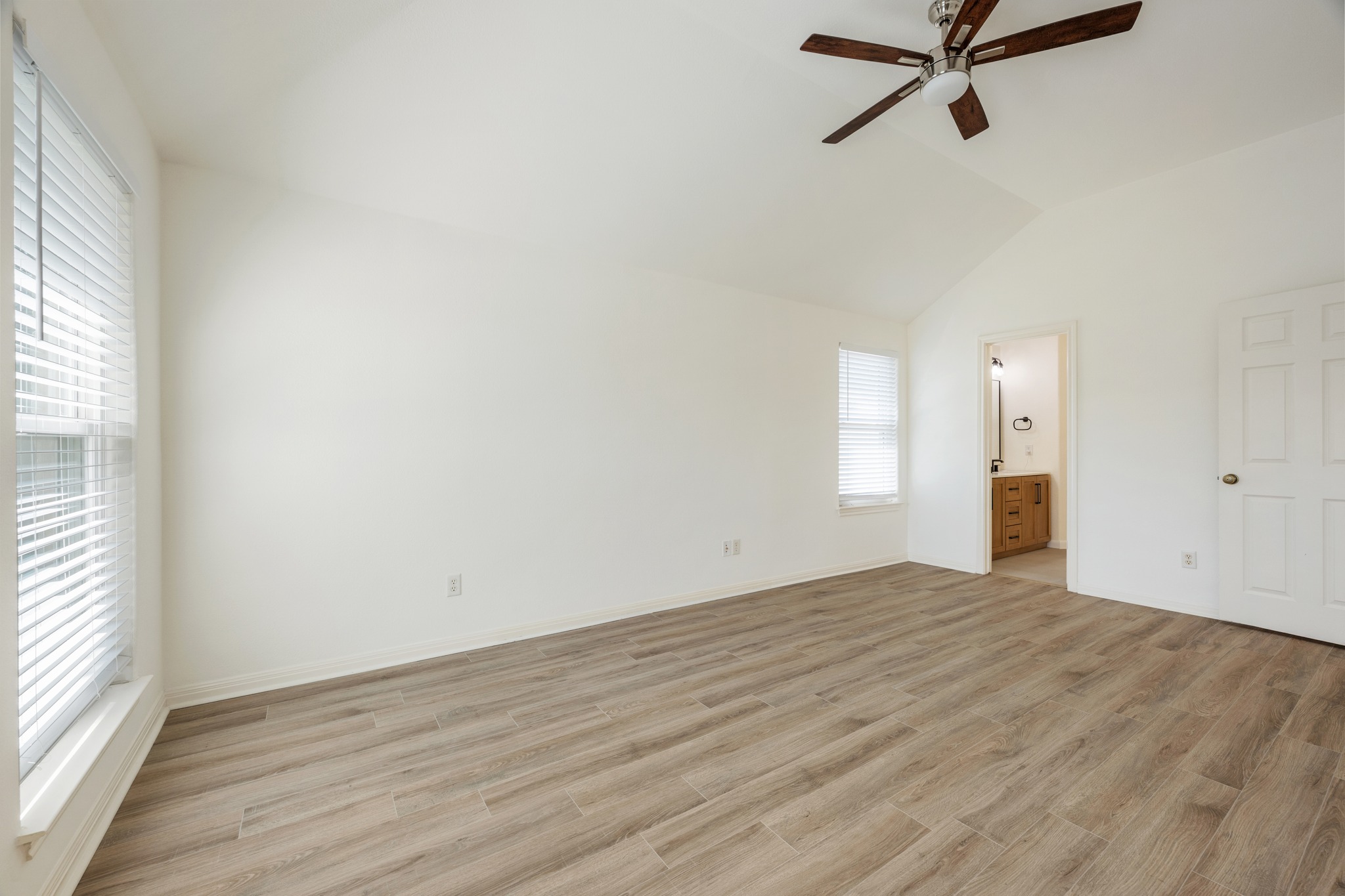 10114 Janet Loop Dripping Springs, TX 78620 - Photo 15 of 34 Vaulted ceilings and wood-look flooring enhance this inviting, sunlit bedroom space.