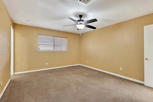 an empty room with a window and a fan