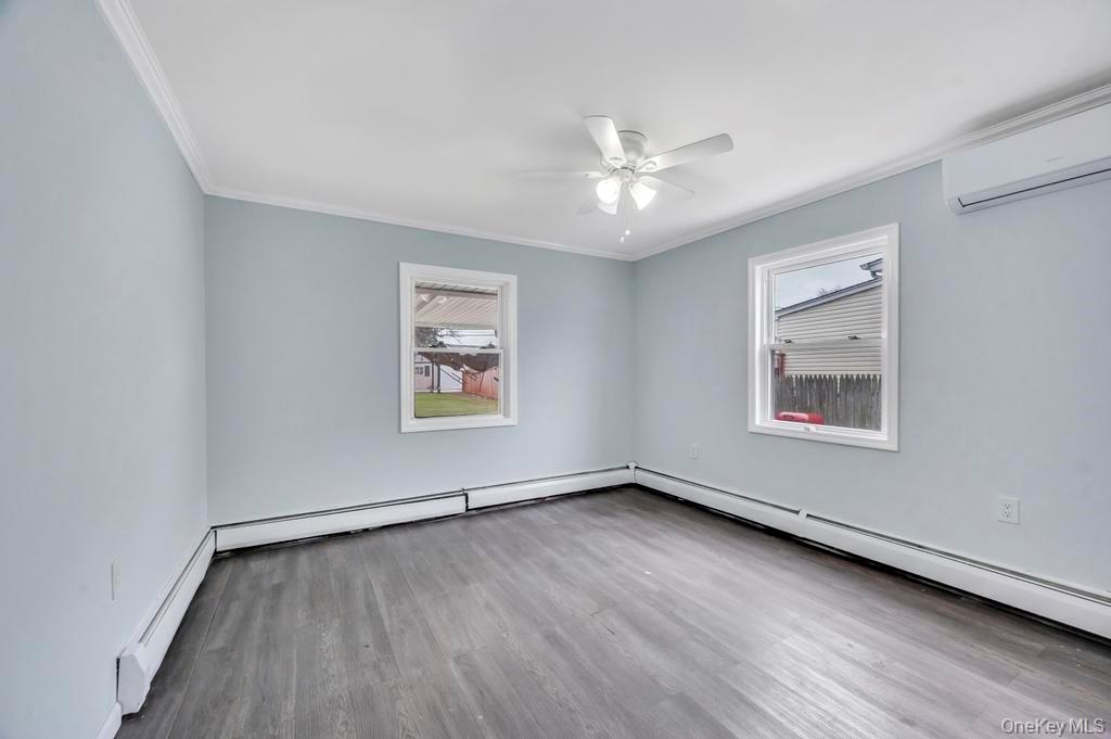 63 Blacksmith Road Levittown, NY 11756 - Photo 12 of 25 Unfurnished room featuring a baseboard radiator, light wood finished floors, a baseboard heating unit, ceiling fan, and crown molding