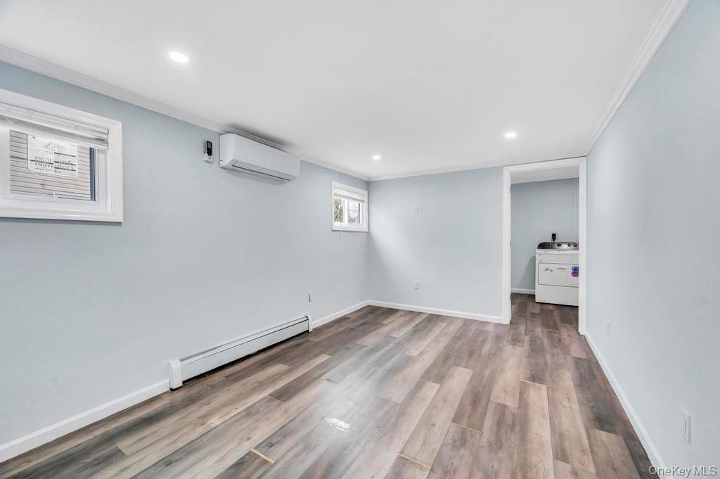 63 Blacksmith Road Levittown, NY 11756 - Photo 15 of 25 Basement with a baseboard radiator, light wood-style floors, recessed lighting, ornamental molding, and washer / clothes dryer