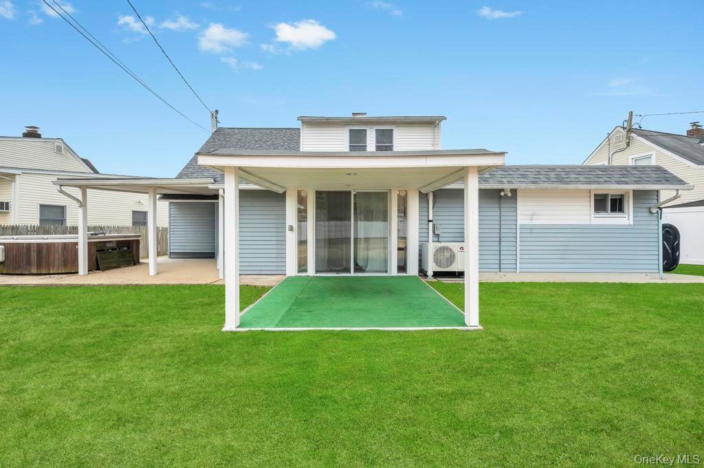 63 Blacksmith Road Levittown, NY 11756 - Photo 23 of 25 Rear view of house featuring a patio, a hot tub, a yard, a shingled roof, and heating fuel