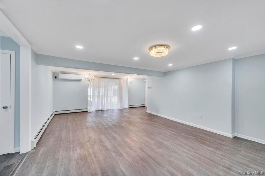 63 Blacksmith Road Levittown, NY 11756 - Photo 5 of 25 Unfurnished living room featuring wood finished floors, a baseboard radiator, hanging lights, and a baseboard heating unit
