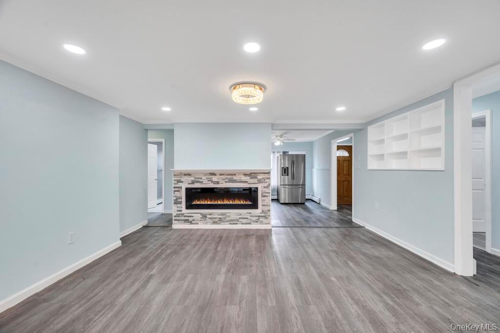 63 Blacksmith Road Levittown, NY 11756 - Photo 7 of 25 Unfurnished living room with a tiled fireplace, recessed lighting, dark wood finished floors, ceiling fan, and a baseboard heating unit