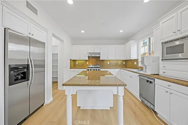 a kitchen with stainless steel appliances granite countertop a sink refrigerator and cabinets