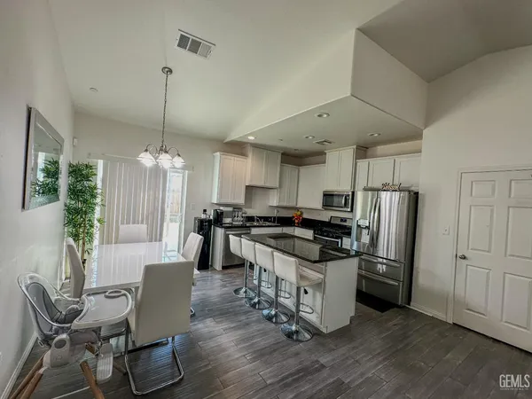a kitchen with stainless steel appliances a dining table chairs stove refrigerator and cabinets