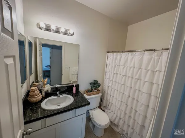 a bathroom with a granite countertop sink and a mirror with toilet