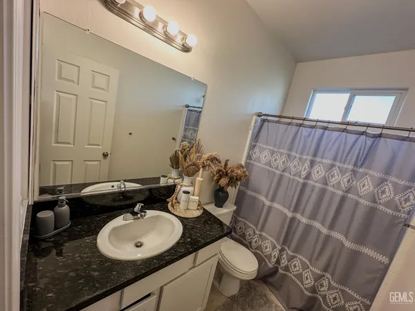 a bathroom with a granite countertop double vanity sink mirror and toilet