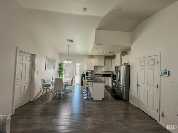 a kitchen with stainless steel appliances a stove a refrigerator cabinets dining table and chairs