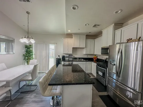 a kitchen with granite countertop stainless steel appliances a refrigerator a stove a sink a center island and chairs