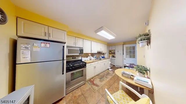 a kitchen with stainless steel appliances a refrigerator sink and white cabinets