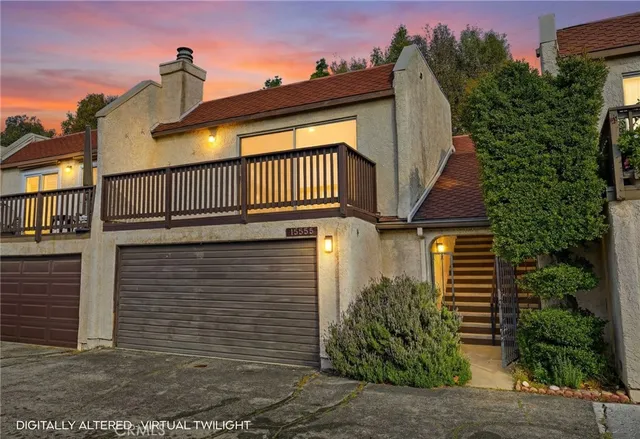 a view of a brick house with plants and wooden fence