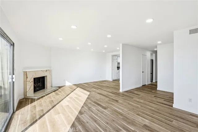 a view of an empty room with wooden floor fireplace and a window
