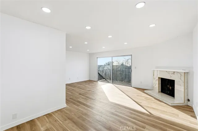 a view of an empty room with wooden floor and a fireplace