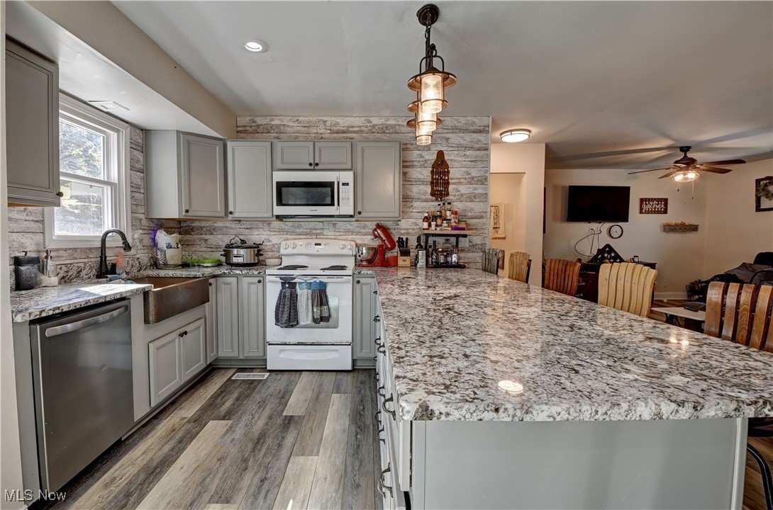 4244 Murray Road Dover, OH 44622 - Photo 3 of 29 Kitchen featuring white appliances, light stone countertops, gray cabinetry, a peninsula, and light wood-style floors