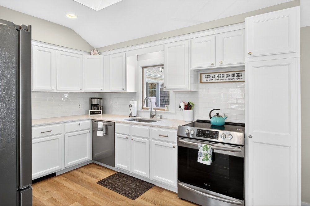 40 Shore Road Dennis, MA 02670 - Photo 12 of 34 a kitchen with stainless steel appliances granite countertop a stove a sink and white cabinets