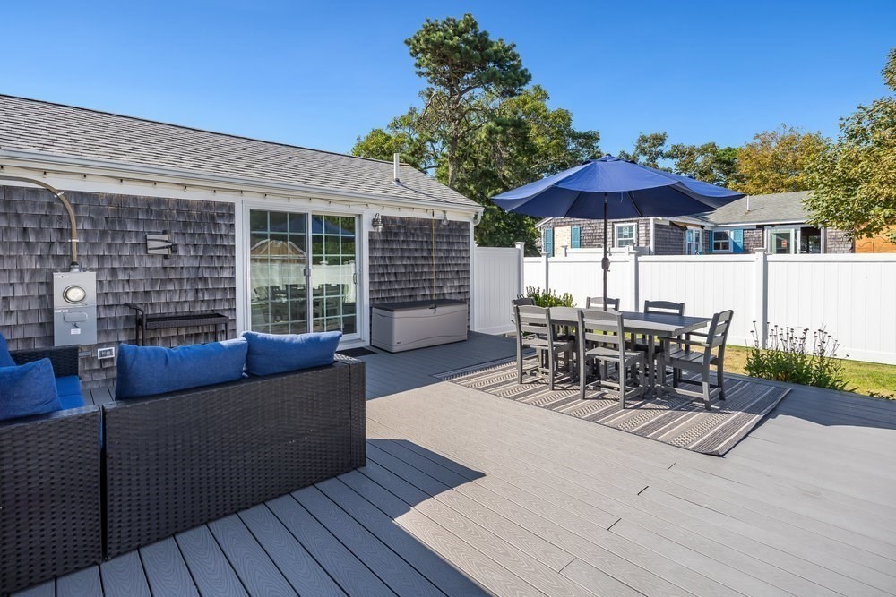 40 Shore Road Dennis, MA 02670 - Photo 25 of 34 a view of a patio with couches table and chairs under an umbrella with wooden floor