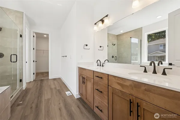 a spacious bathroom with a double vanity sink a mirror and a shower