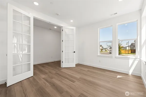 an empty room with wooden floor and windows