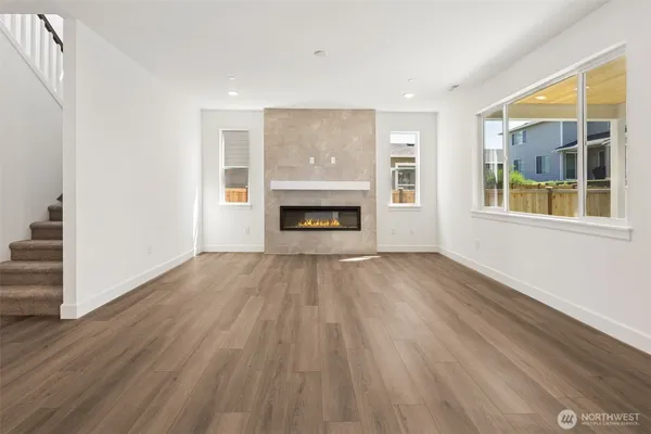 an empty room with wooden floor fireplace and windows
