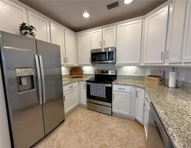 a kitchen with stainless steel appliances granite countertop a refrigerator sink and stove