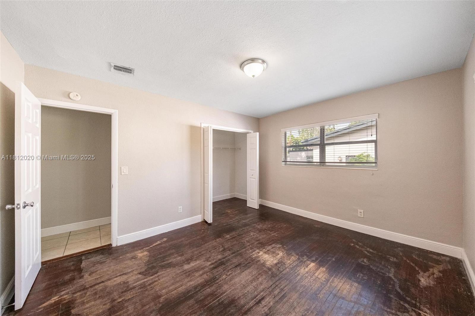 725 Northeast 178th Street Miami, FL 33162 - Photo 11 of 44 a view of an empty room with wooden floor and a window