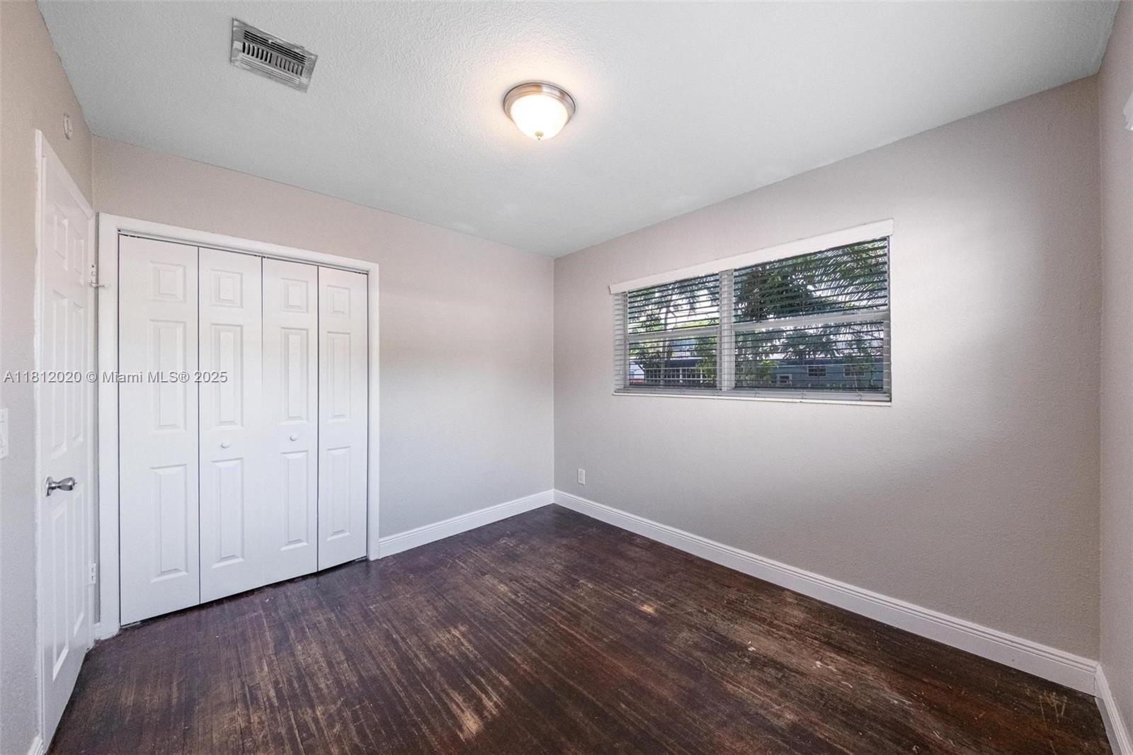 725 Northeast 178th Street Miami, FL 33162 - Photo 16 of 44 a view of an empty room with wooden floor and a window