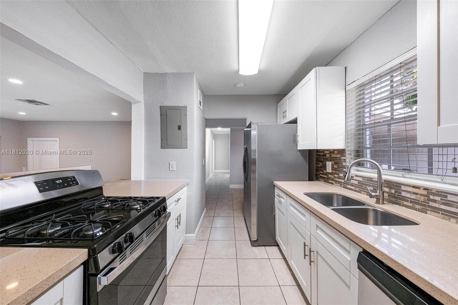 725 Northeast 178th Street Miami, FL 33162 - Photo 28 of 44 a kitchen with a sink stove top oven and cabinets