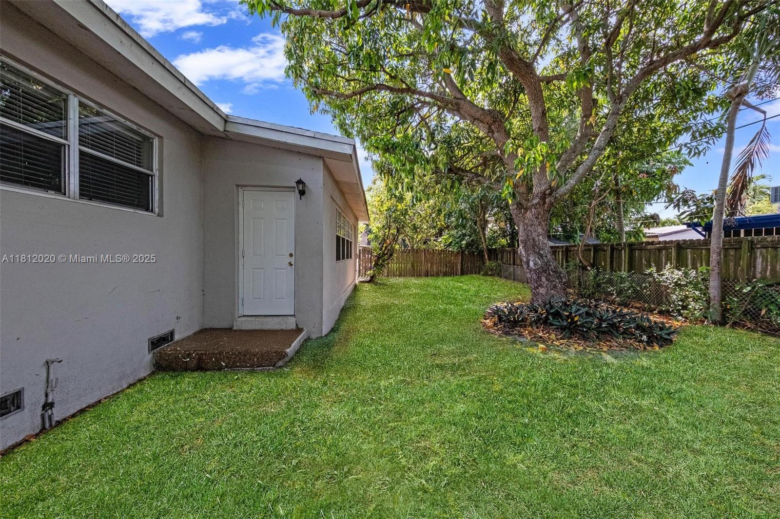 725 Northeast 178th Street Miami, FL 33162 - Photo 41 of 44 a view of backyard with wooden fence and a large tree